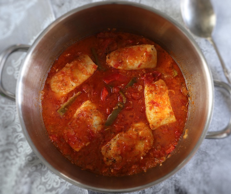 Hake in tomato sauce with peppers in a large saucepan