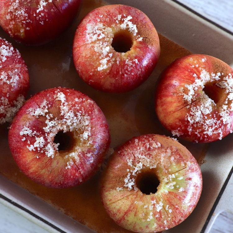 Red apples seasoned with yellow sugar, orange juice, Port wine and cinnamon powder in a baking dish