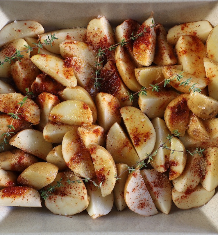 Batata pequenas com casca cortadas em quartos temperadas com sal, pimentão doce, alho em pó, tomilho fresco e azeite numa assadeira